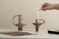 Person lighting a candle in a rustic metal holder with 'Guinon' branding.