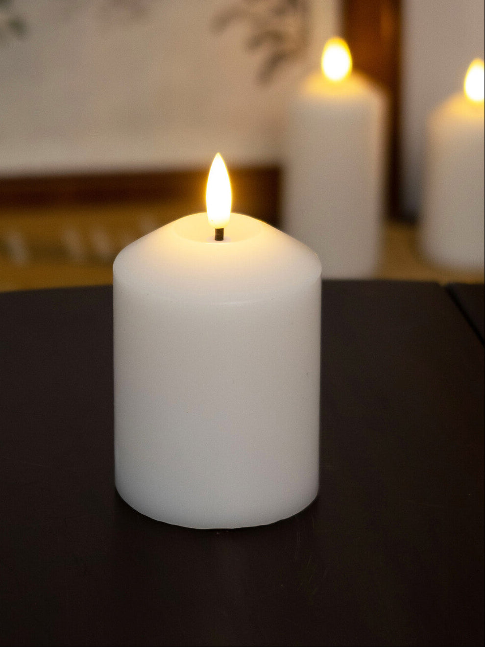 White candles with lit flames on a dark surface, blurred background