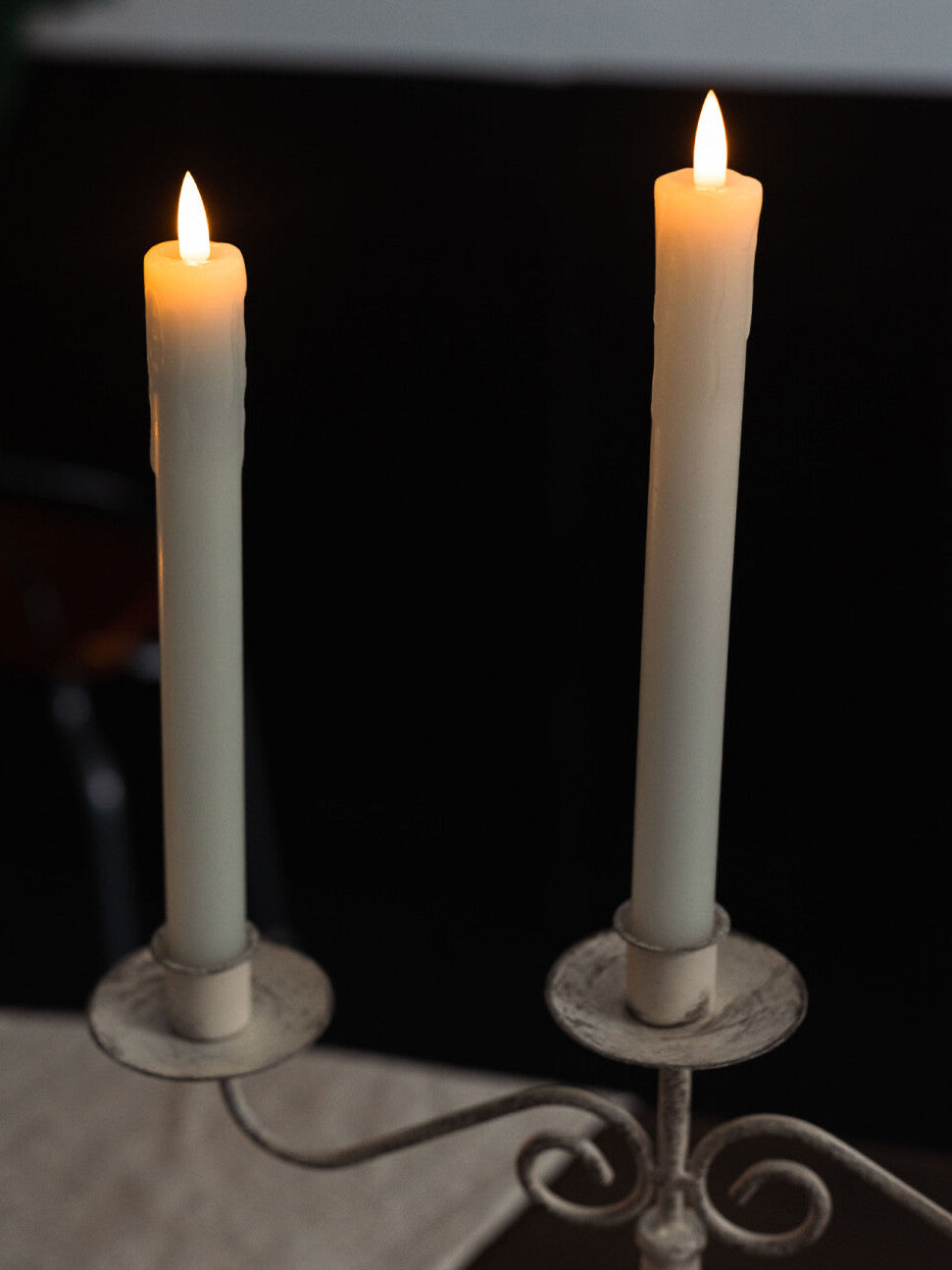 Two lit candles on a decorative candle holder against a dark background