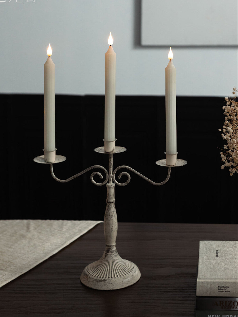 Decorative candle holder with three lit candles on a wooden surface.