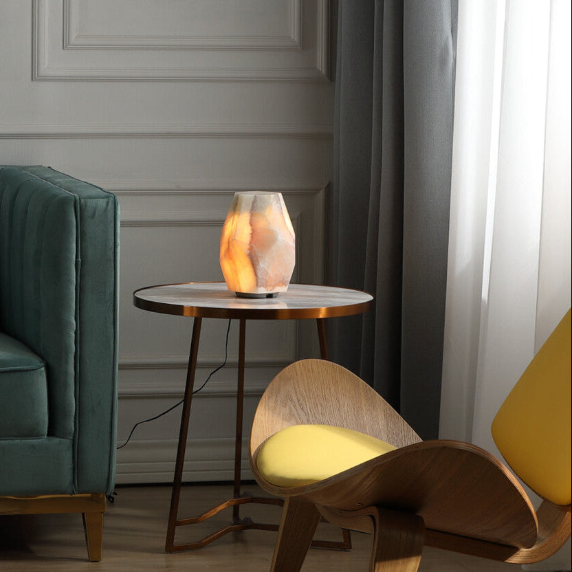 Modern living room with a green sofa, wooden chair, and a small round table with a lamp.