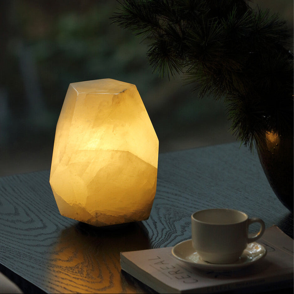 Decorative lamp with a warm glow on a table next to a cup and saucer.
